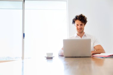 Adam evde dizüstü bilgisayarla çalışıyor.