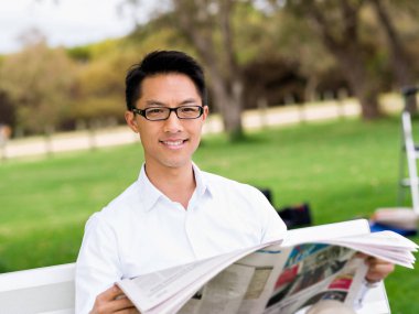 İş adamı parkta bir gazete okuyor