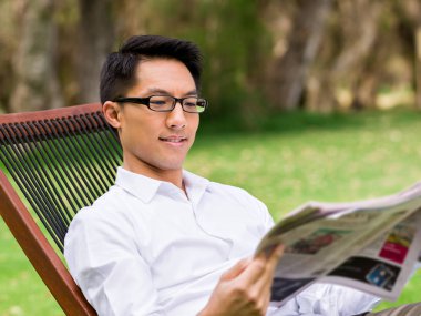 İş adamı parkta bir gazete okuyor