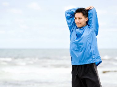 Genç adam sahilde egzersiz yaparak