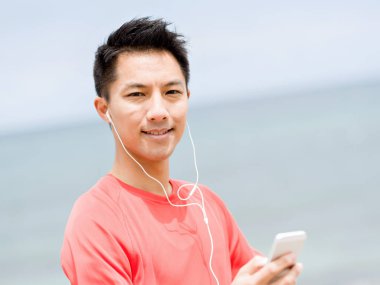 Deniz kıyısında kulaklık sportif adamla