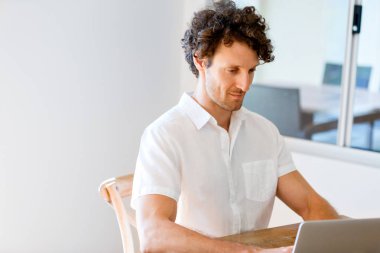 Adam evde dizüstü bilgisayarla çalışıyor.