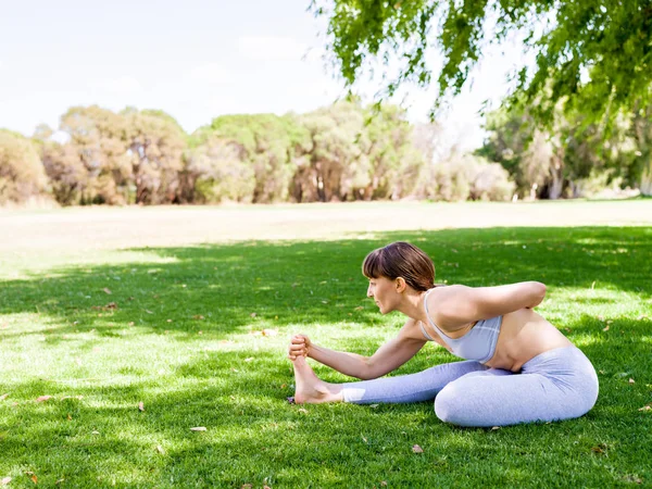 Jonge vrouw het beoefenen van yoga in het park — Stockfoto