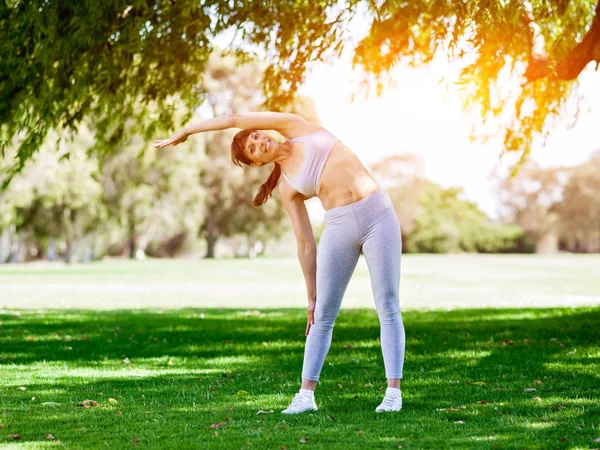 Ung kvinna motionerar i parken — Stockfoto