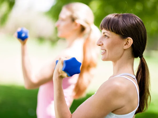 Retrato de mujeres alegres en ropa de fitness haciendo ejercicio con mancuerna — Foto de Stock
