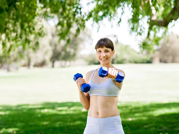 Portrait of cheerful woman in fitness wear exercising with dumbbell — Stock Photo, Image