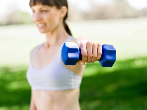 Retrato de mujer alegre en ropa de fitness haciendo ejercicio con mancuerna —  Fotos de Stock