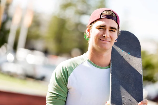 Dospívající chlapec s skateboard stojící venku — Stock fotografie
