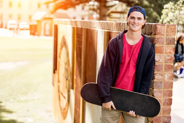 Teenage boy with skateboard standing outdoors — Stock Photo, Image
