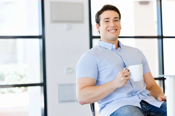 Молодий бізнесмен в офісі з чашкою — стокове фото