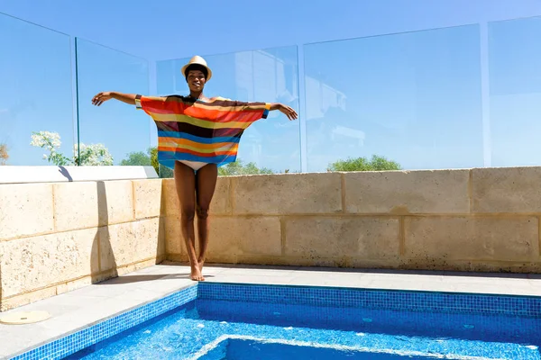 Mujer joven de pie junto a la piscina — Foto de Stock