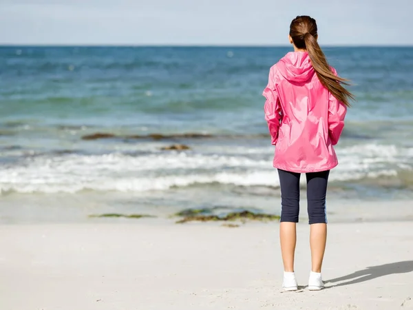 Sportieve vrouw in sportkleding staande aan de kust — Stockfoto