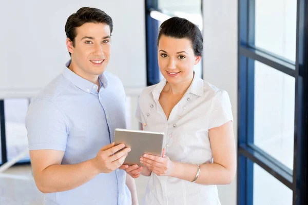Giovane e donna con touchpad in piedi in ufficio — Foto Stock