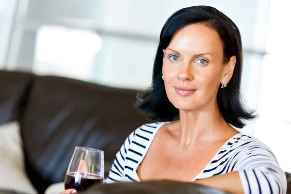 Beautiful young woman holding glass with red wine — Stock Photo, Image