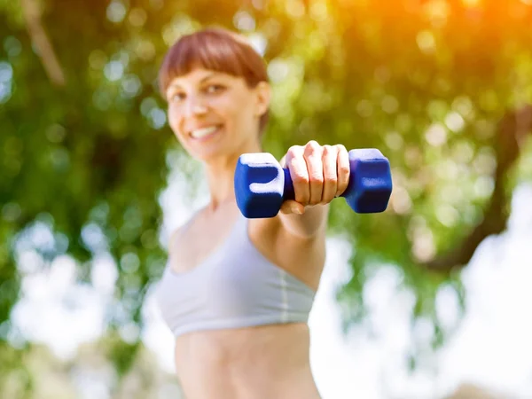 Portrait of cheerful woman in fitness wear exercising with dumbbell — Stock Photo, Image