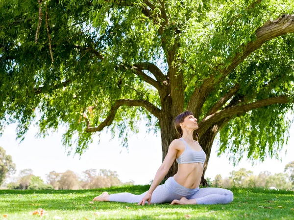 Young woman practicing yoga in the park — Stock Photo, Image