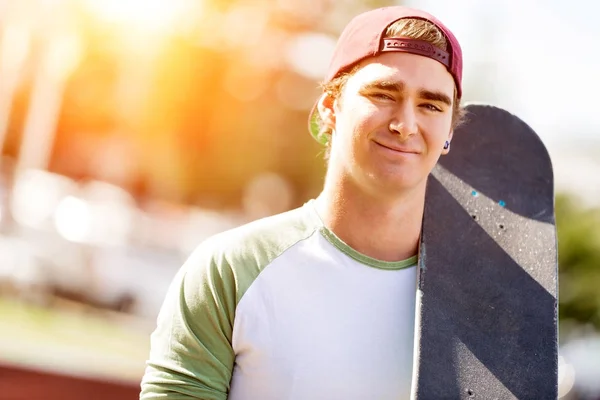 Teenage boy with skateboard standing outdoors — Stock Photo, Image