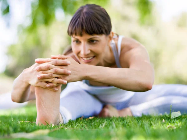 Jeune femme pratiquant le yoga dans le parc — Photo