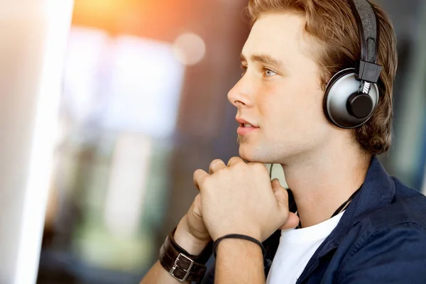 Junger Mann mit Kopfhörern im Büro Stockbild