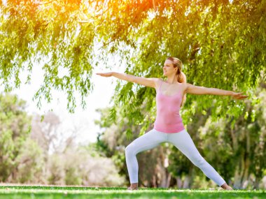 Parkta yoga yapan genç kadın.