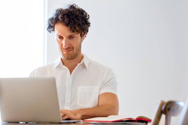 Adam evde dizüstü bilgisayarla çalışıyor.