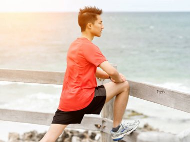 Genç adam sahilde egzersiz yaparak