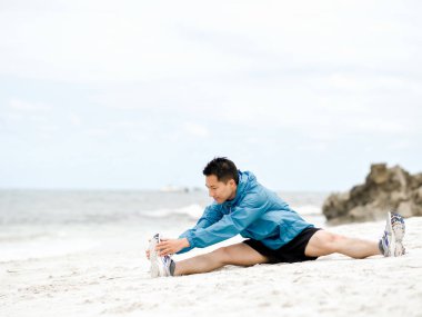 Genç adam sahilde egzersiz yaparak