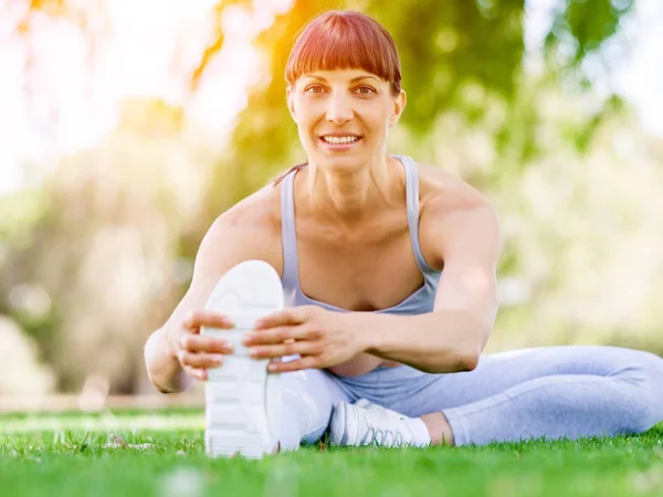 Parkta egzersiz yapan genç bir kadın.