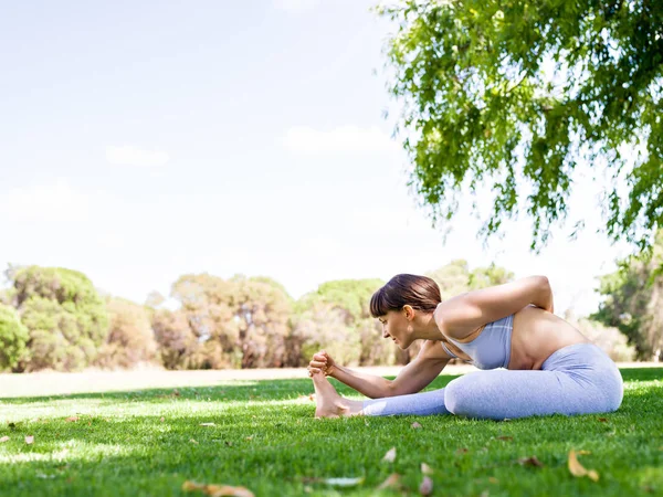 Jonge vrouw het beoefenen van yoga in het park — Stockfoto