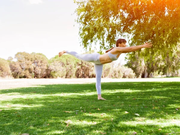 Giovane donna che pratica yoga nel parco — Foto Stock