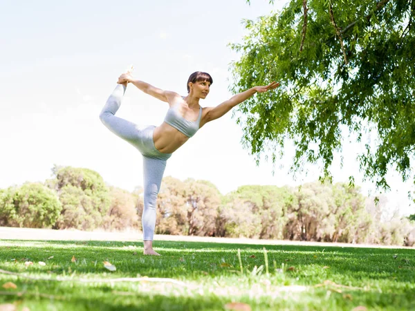 Giovane donna che pratica yoga nel parco — Foto Stock