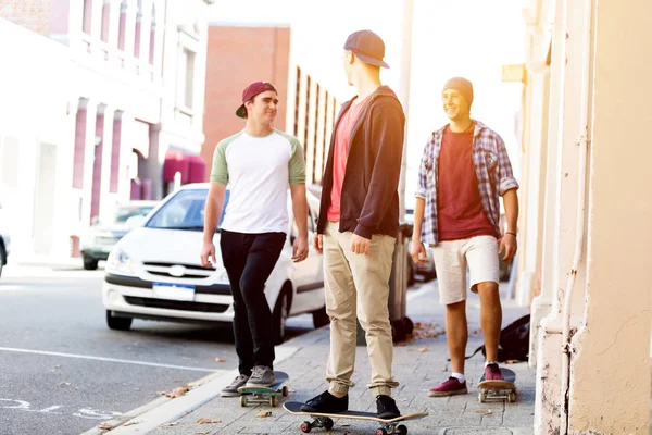 Teenage friends walking at the street with skateboards — Stock Photo, Image
