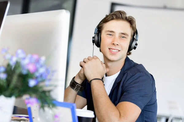 Νεαρός άνδρας στο γραφείο με τα ακουστικά — Φωτογραφία Αρχείου