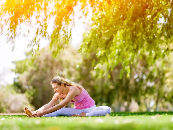 Молода жінка робить йогу в парку — стокове фото