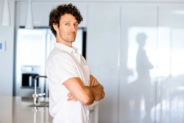 Retrato de un joven inteligente de pie en la cocina — Foto de Stock