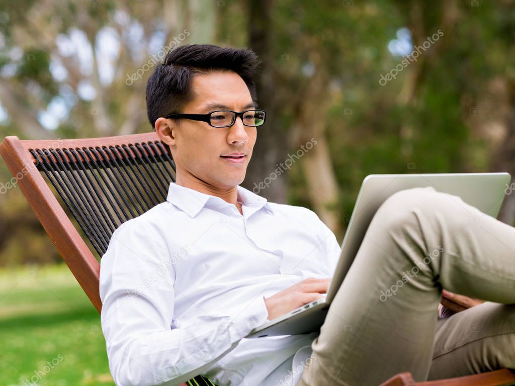 Young businessman using laptop while sitting outdoors