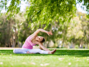 Parkta yoga yapan genç kadın.