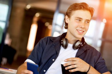 Kendine güvenen genç adam akıllı rahat kıyafet telefon tutarak