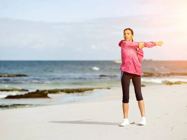 Ung kvinna på stranden gör övningar — Stockfoto