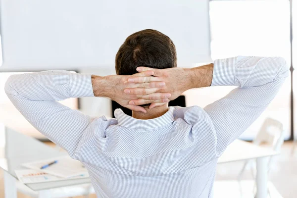 Rear view of sitting businessman with crossed hands on the head — Stock Photo, Image
