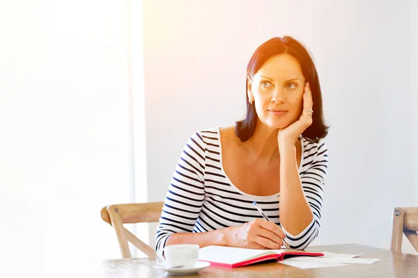 Mulher bonita escrevendo em uma agenda em casa ou escritório — Fotografia de Stock