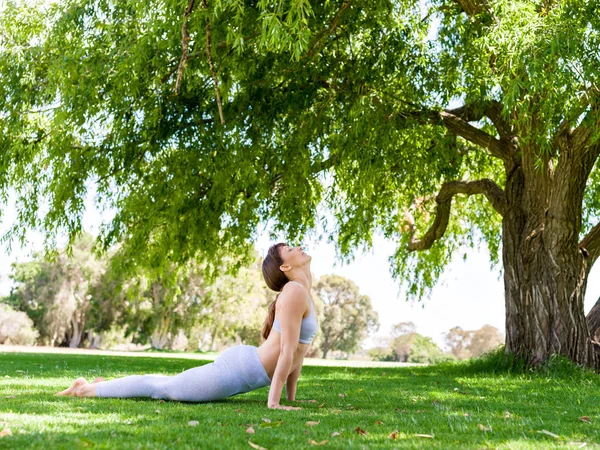 Mladá žena cvičí jógu v parku — Stock fotografie