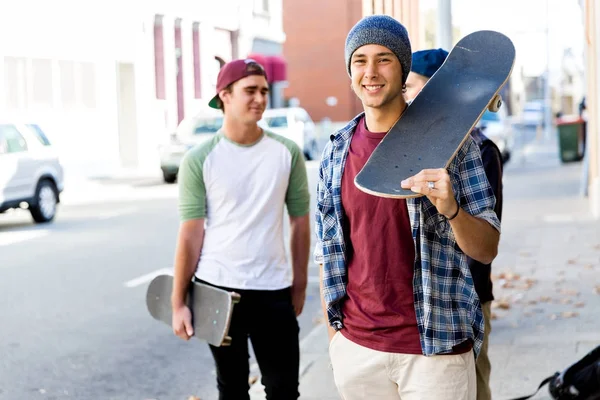 Adolescente menino andando na rua com seu skate — Fotografia de Stock