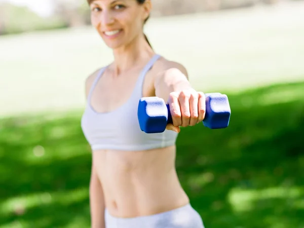 Retrato de mujer alegre en ropa de fitness haciendo ejercicio con mancuerna — Foto de Stock