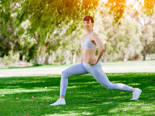 Ung kvinna motionerar i parken — Stockfoto