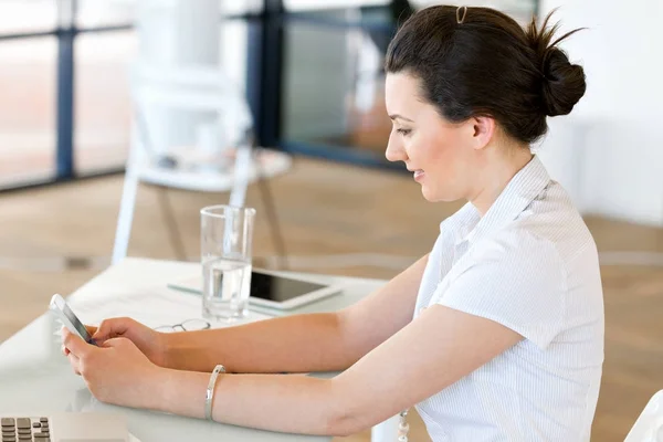 Affärskvinna med mobiltelefon i office — Stockfoto