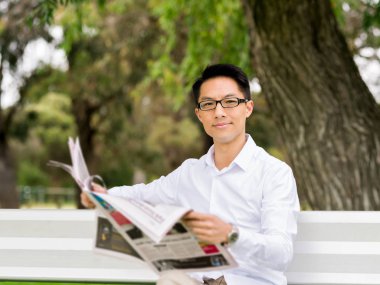 İş adamı parkta bir gazete okuyor