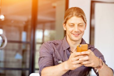 Kendine güvenen genç adam akıllı rahat kıyafet telefon tutarak