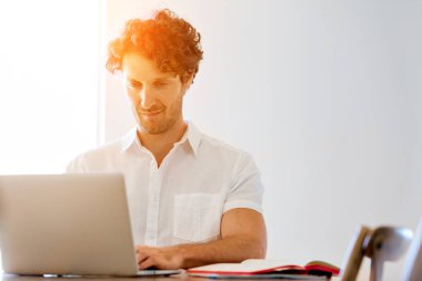 Adam evde dizüstü bilgisayarla çalışıyor.