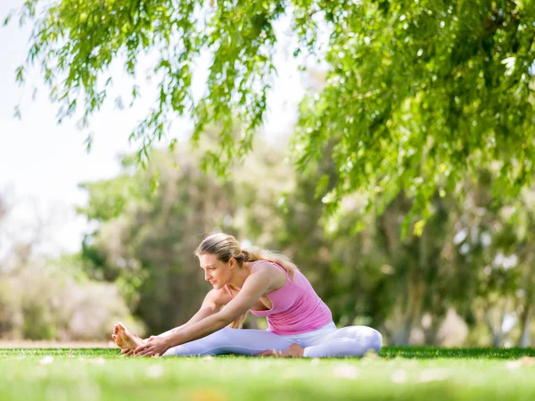 Молода жінка робить йогу в парку — стокове фото